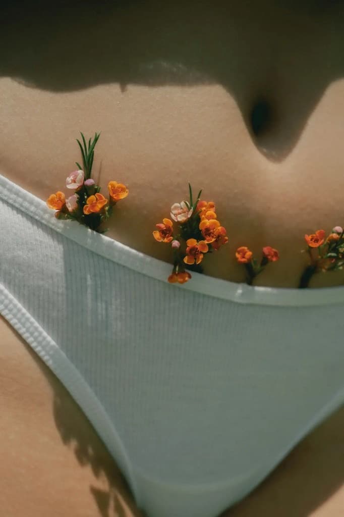 Nahaufnahme eines Bauchs mit kleinen Blüten am Bund einer hellen Unterhose